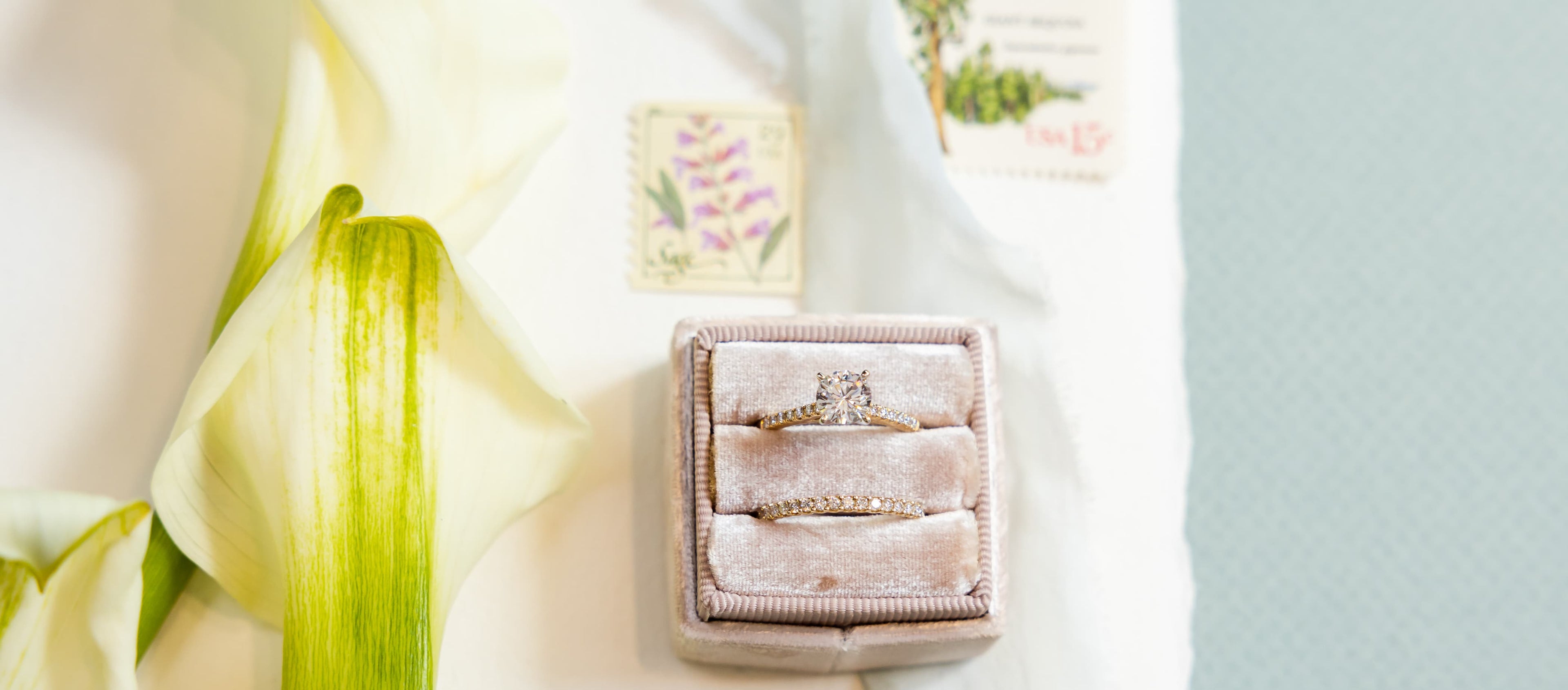 Engagement ring against a calla lily and a pair of stamps