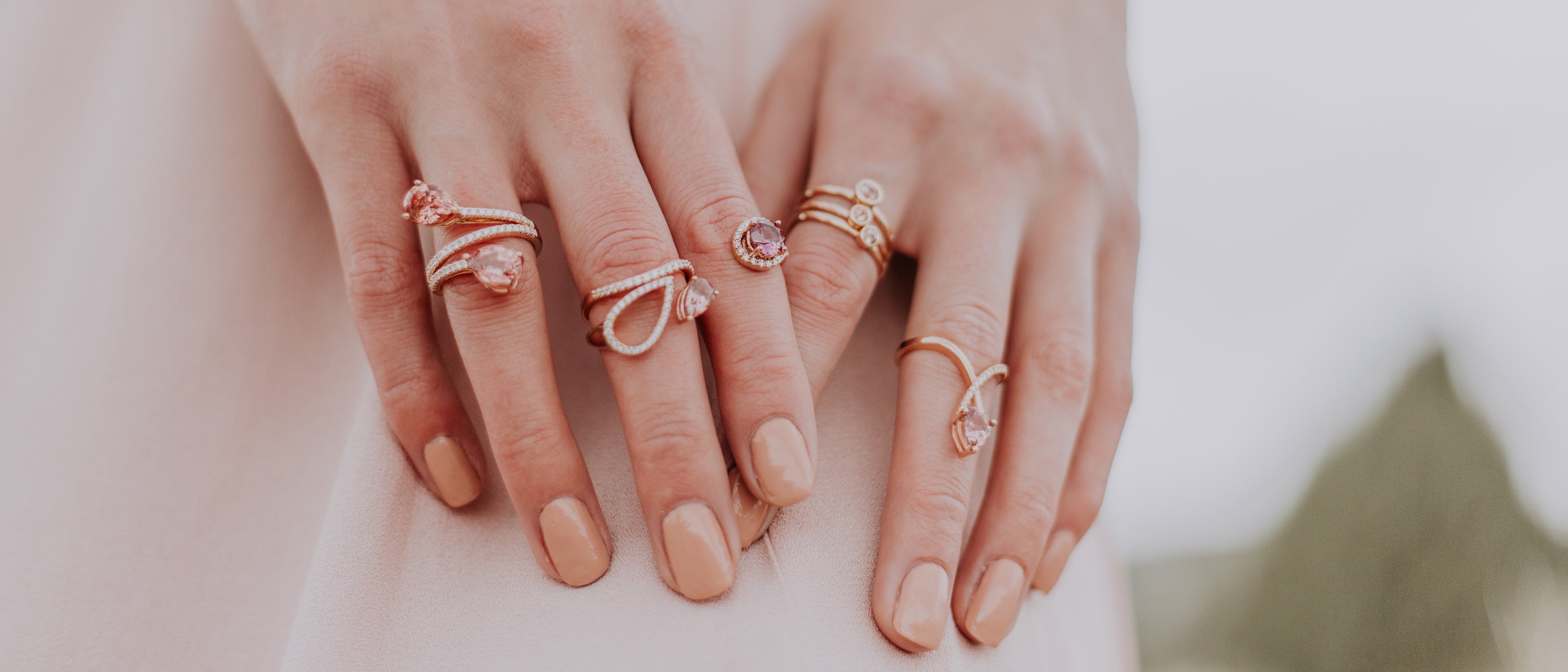 A pair of hands wearing assorted fashion rings with various gems