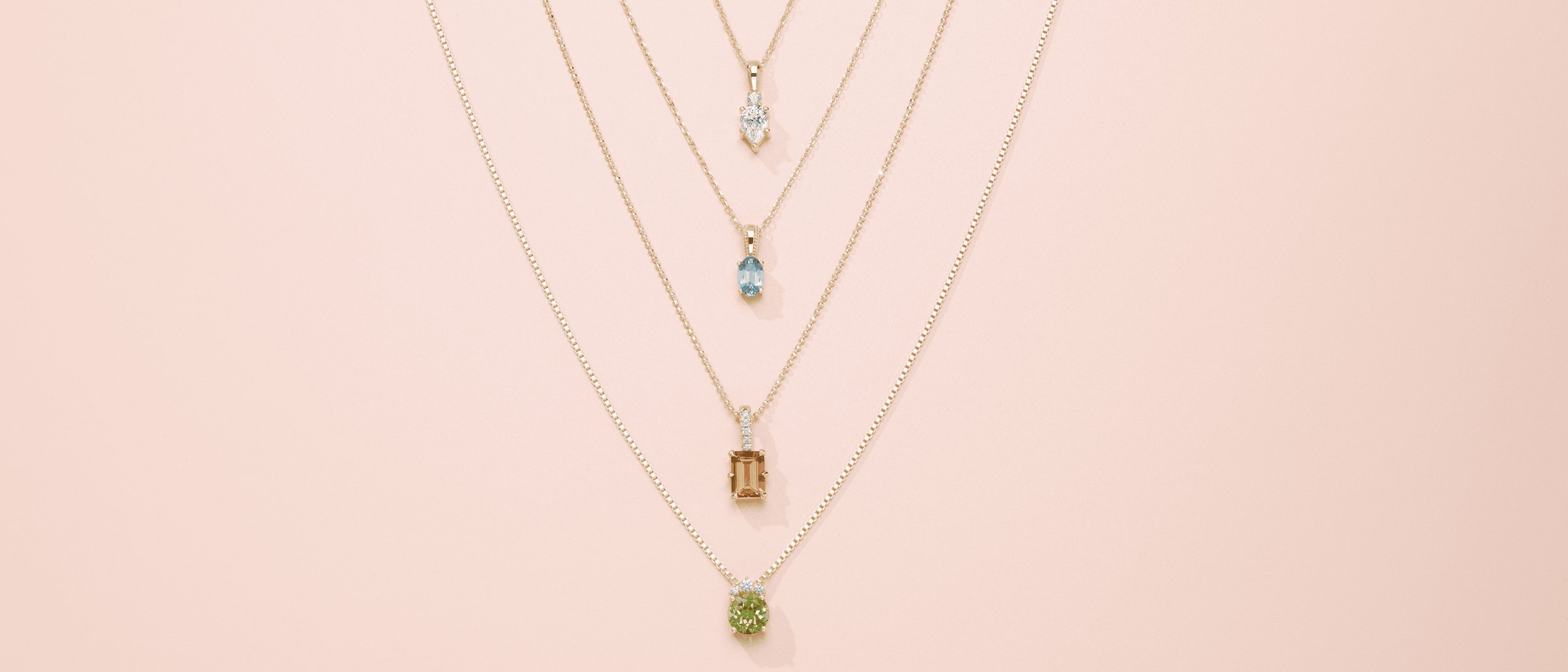 Four gemstone pendants stacked on a pink background