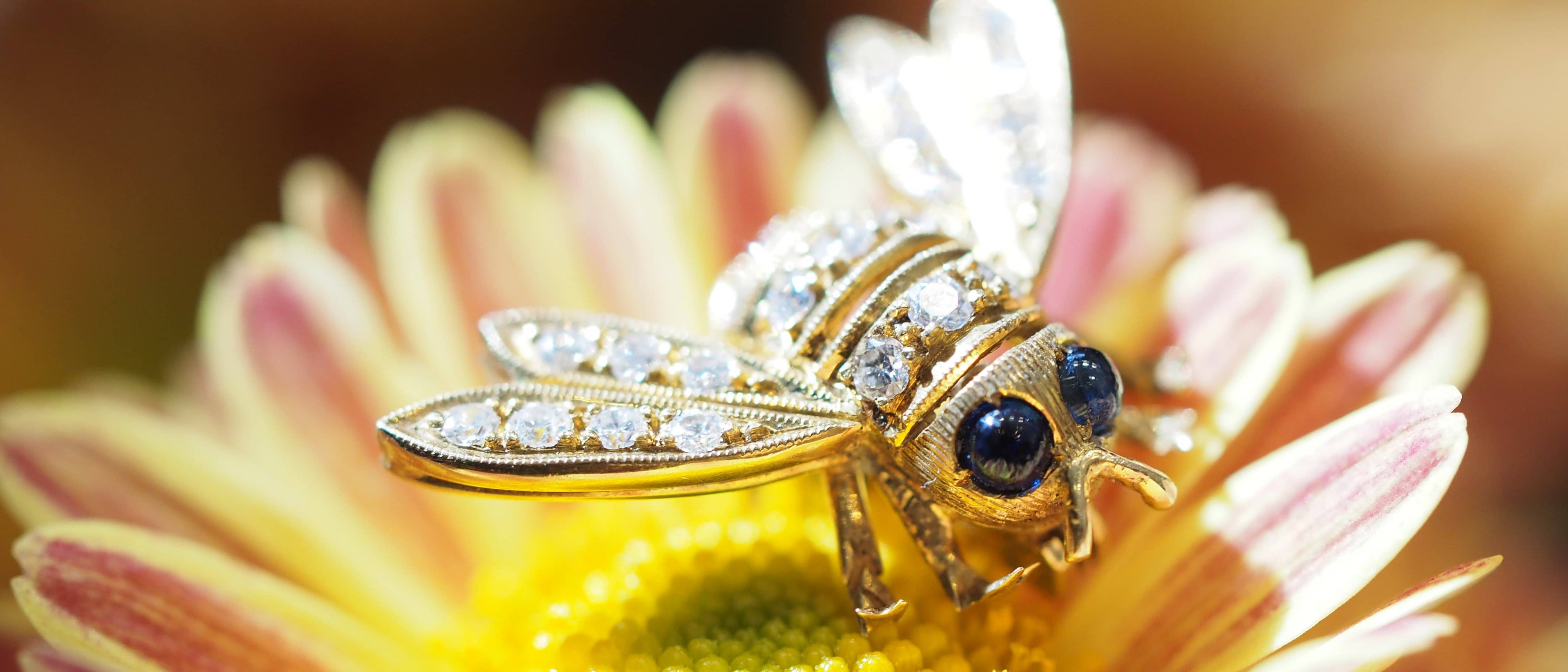 A bumblebee made of diamonds with round sapphires for eyes, on a real flower