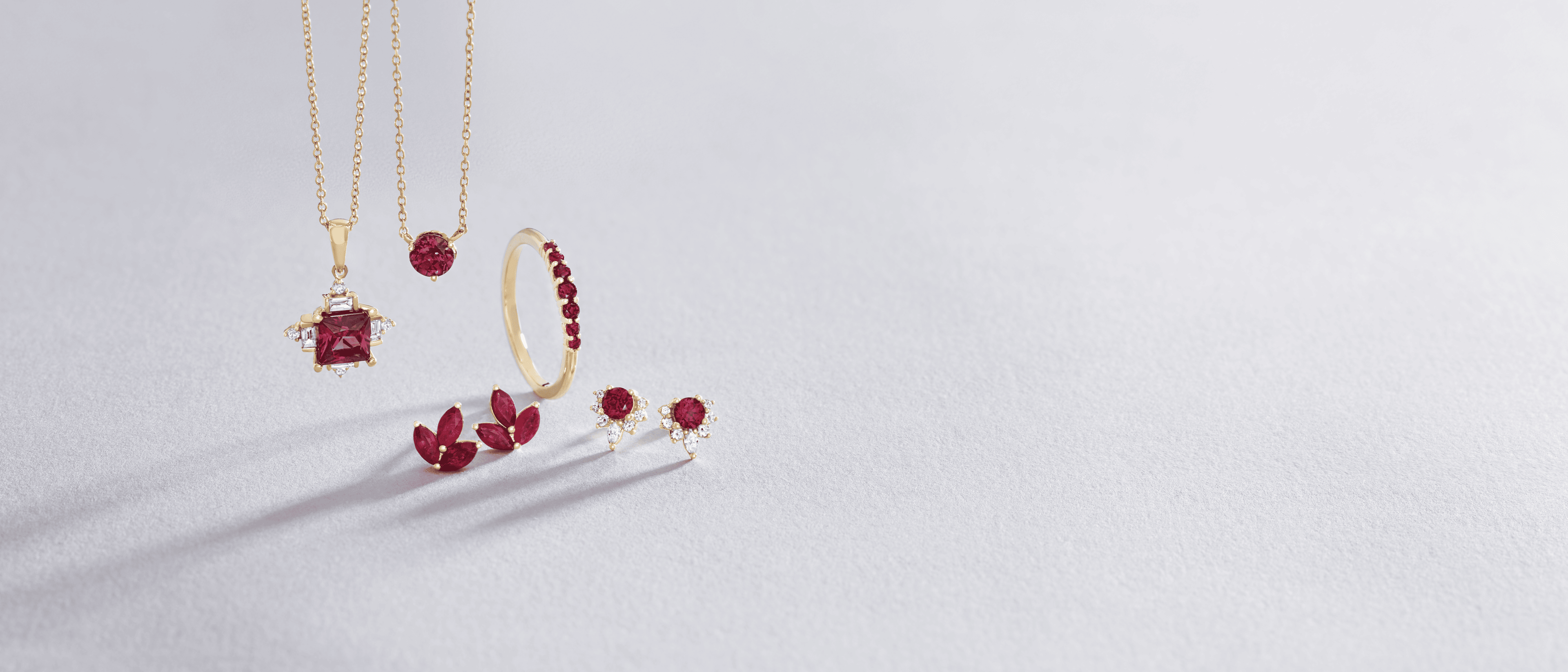 Assorted women's gold and ruby jewelry against a white background